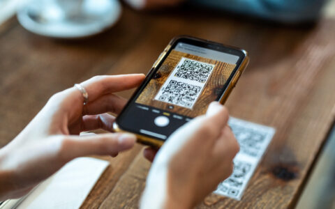 Young woman hands using the smart phone to scan the qr code to s